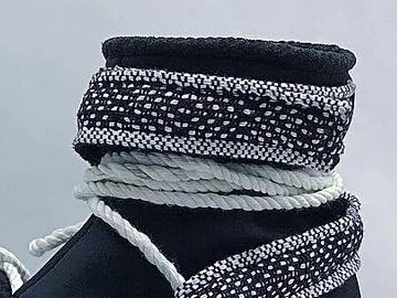 Close-up of cream cloth rope wound around the ankle under a woven collar strap
