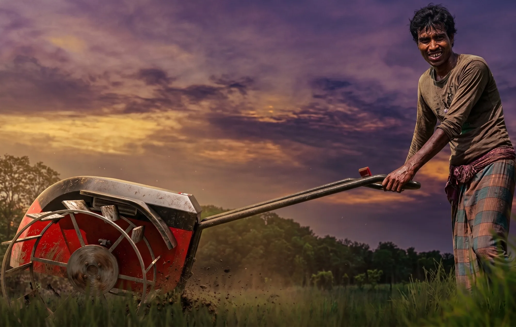 Farmer steering the red E-kuliglig hand tractor through a field at sunset