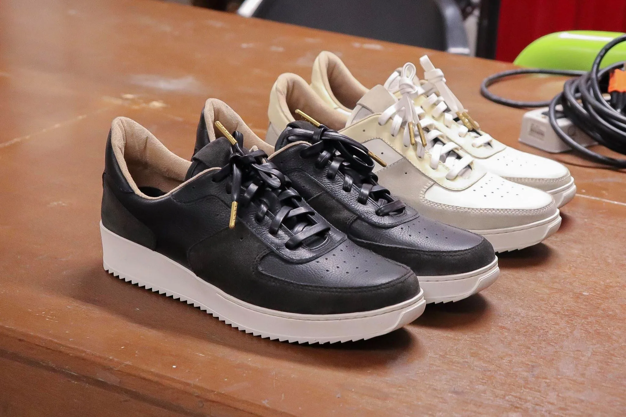 Black and cream PAMBA sneakers side by side on a workbench
