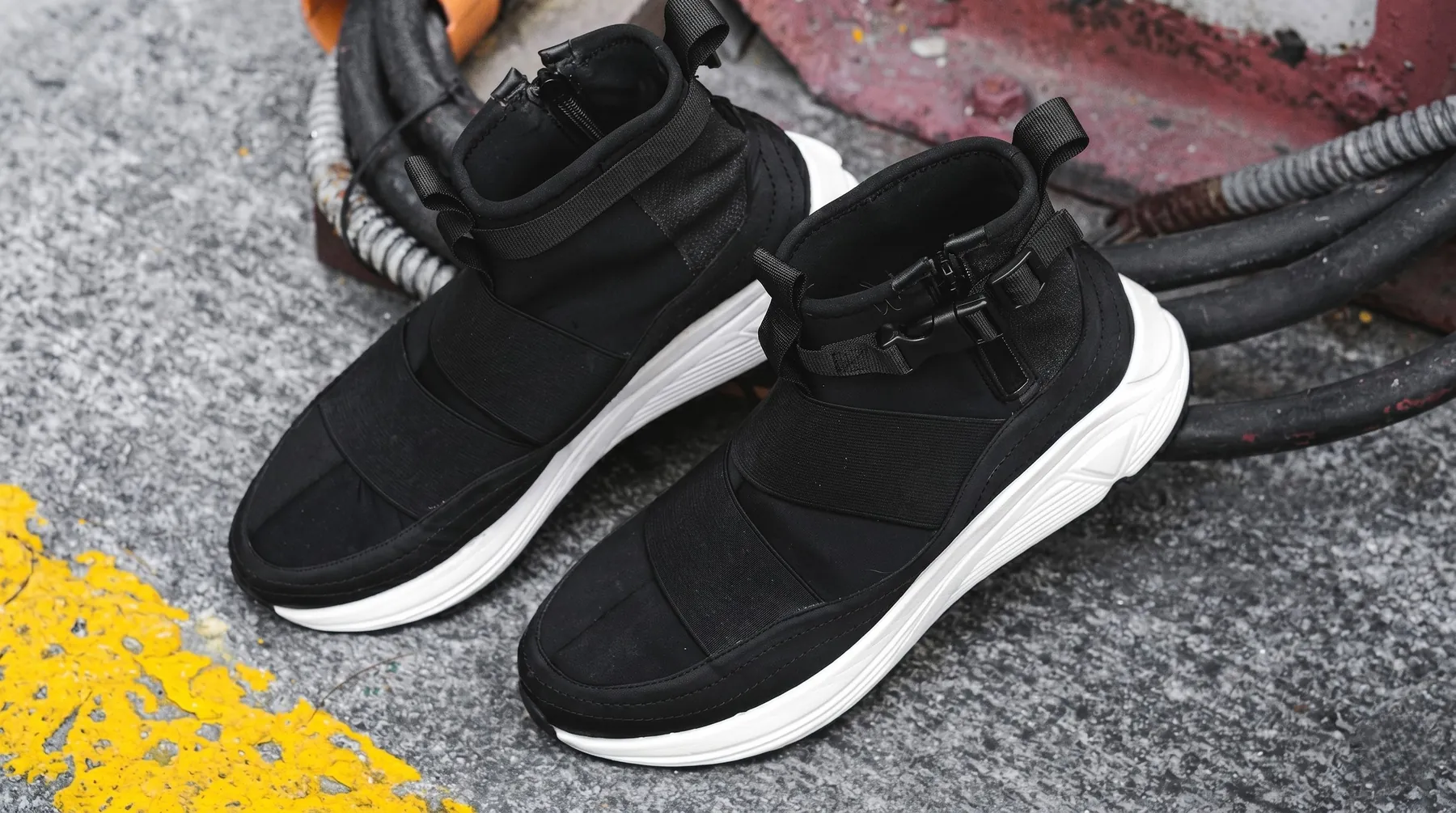Wave sneakers on wet asphalt next to a yellow road line and cables